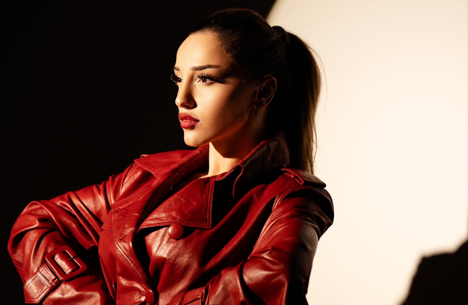 Nutsa Buzaladze in a red pleather coat in a spotlight