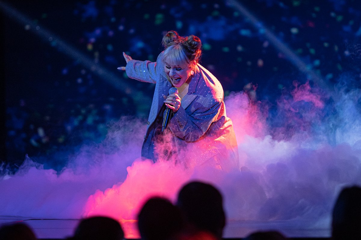 Söngvakeppnin 2023 winner Diljá sings into a microphone, surrounded by pink and blue stage lights and smoke