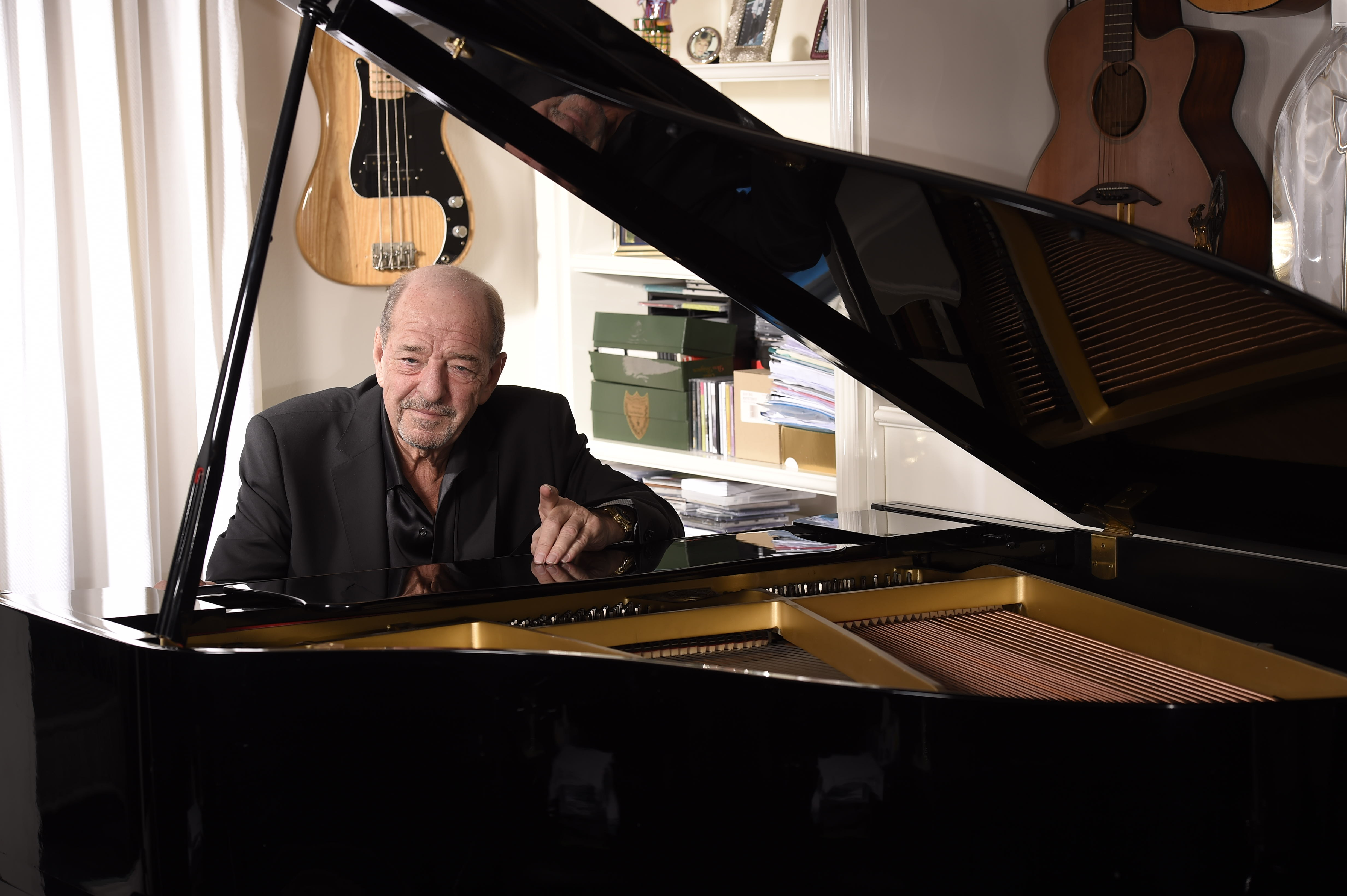 Ralph Siegel, an older white man, is sitting behind a black grand piano